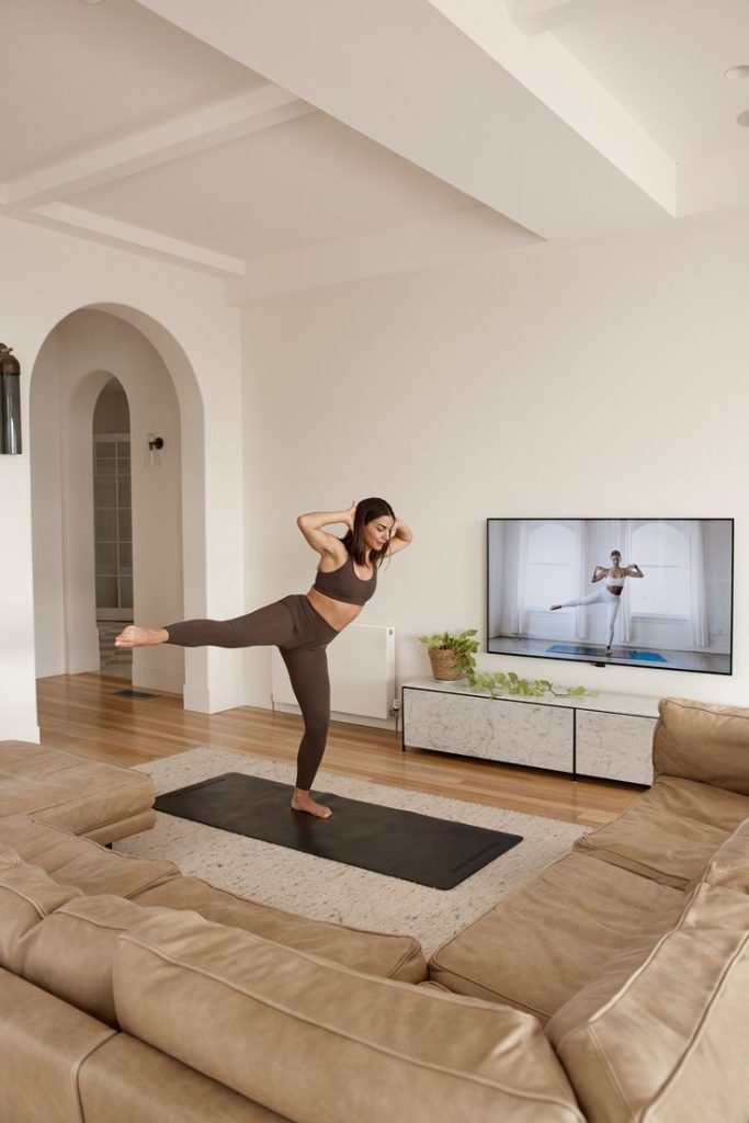 woman doing yoga at home with yoga class at the TV